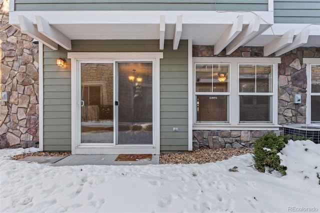 snow covered property entrance with cooling unit