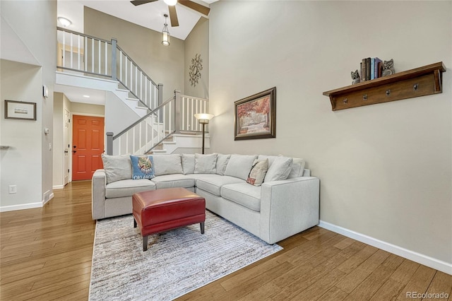 living room featuring ceiling fan, a towering ceiling, and hardwood / wood-style floors