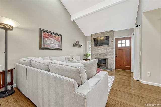 living room featuring hardwood / wood-style flooring, a brick fireplace, high vaulted ceiling, and beamed ceiling