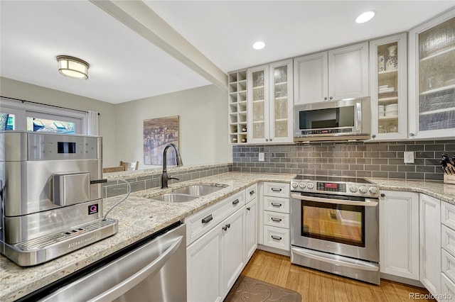 kitchen featuring sink, white cabinetry, stainless steel appliances, tasteful backsplash, and light stone counters