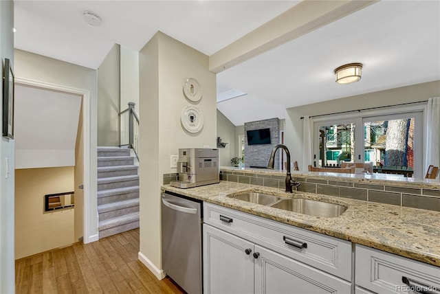 kitchen with sink, white cabinetry, light stone counters, light wood-type flooring, and dishwasher