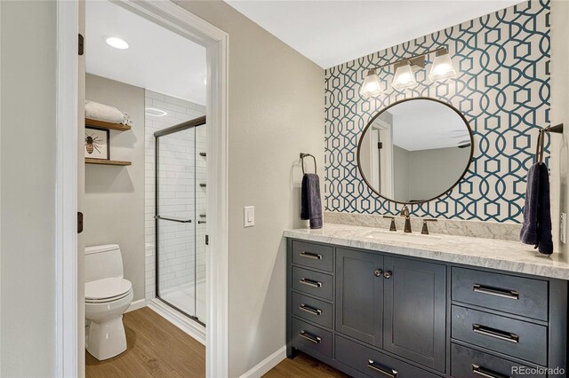 bathroom featuring wood-type flooring, a shower with shower door, and toilet