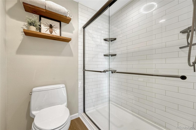 bathroom with wood-type flooring, toilet, and an enclosed shower