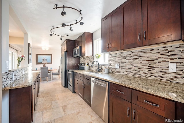 kitchen featuring light stone counters, stainless steel appliances, backsplash, and sink