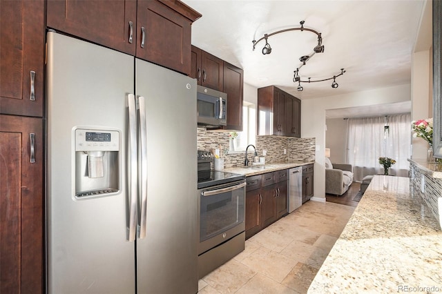 kitchen with sink, tasteful backsplash, light stone counters, and appliances with stainless steel finishes