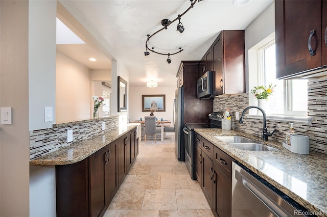 kitchen with appliances with stainless steel finishes, decorative backsplash, light stone countertops, and sink