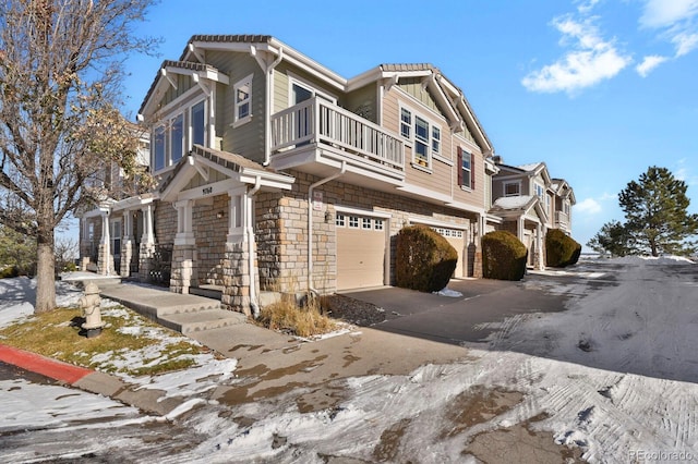 snow covered property with a balcony and a garage