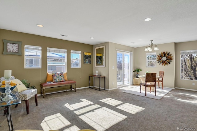 living area featuring a healthy amount of sunlight, light colored carpet, and a notable chandelier