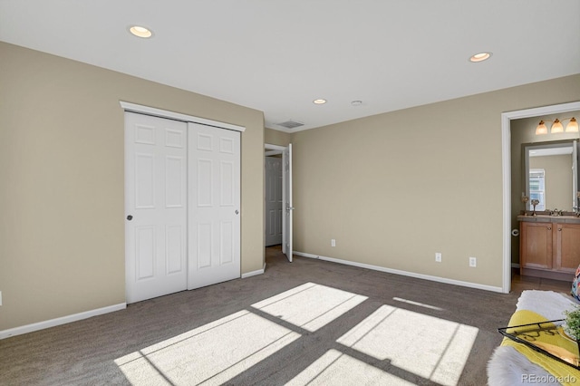 unfurnished bedroom featuring dark colored carpet, connected bathroom, and a closet