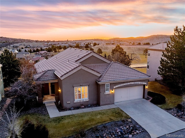 view of front facade featuring an attached garage, a tiled roof, stucco siding, driveway, and a mountain view