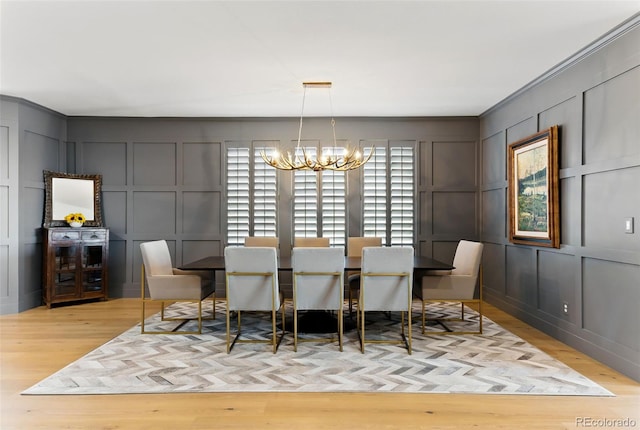 dining area featuring a decorative wall, wood finished floors, and a chandelier