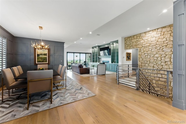 dining room featuring light wood finished floors, recessed lighting, a fireplace, and an inviting chandelier