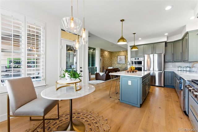 kitchen featuring tasteful backsplash, light wood-style flooring, stainless steel appliances, and light countertops