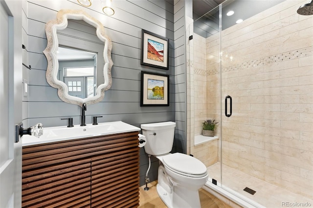 bathroom featuring toilet, a stall shower, and vanity