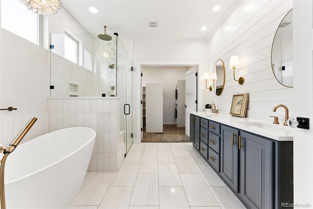 bathroom with double vanity, a freestanding tub, a stall shower, and a sink