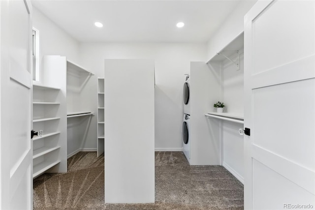 spacious closet featuring stacked washer / dryer and carpet flooring