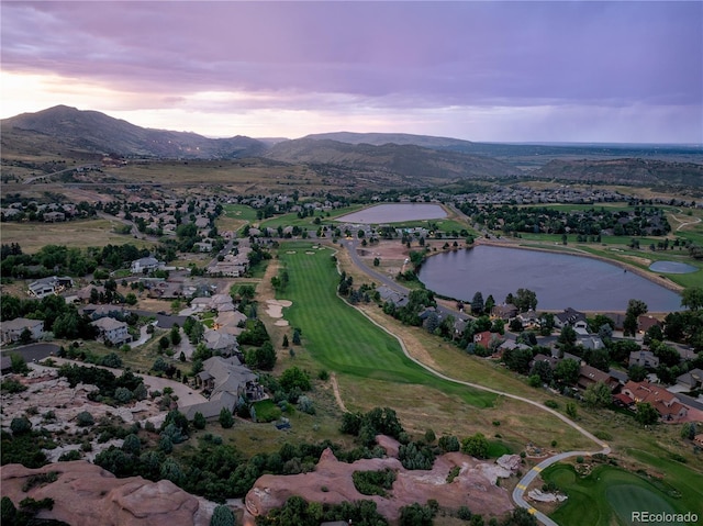 aerial view at dusk featuring a water and mountain view