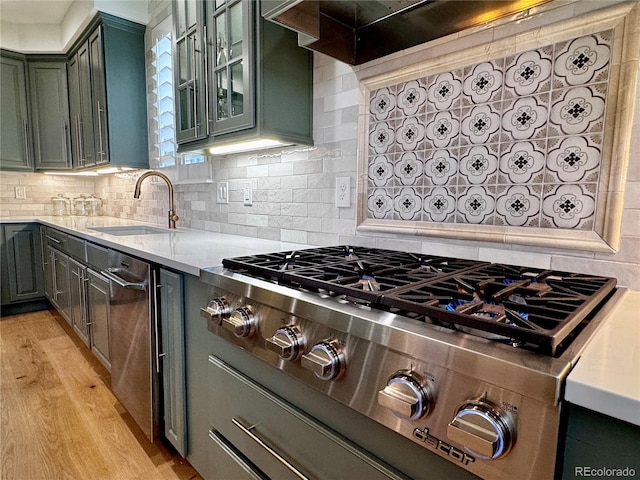 kitchen with stainless steel gas cooktop, backsplash, a sink, and light wood-style flooring
