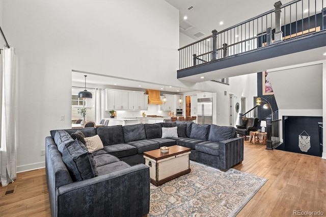 living room with light wood-type flooring and a towering ceiling