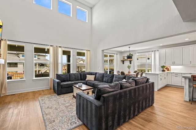 living room with a wealth of natural light, a high ceiling, and light wood-type flooring