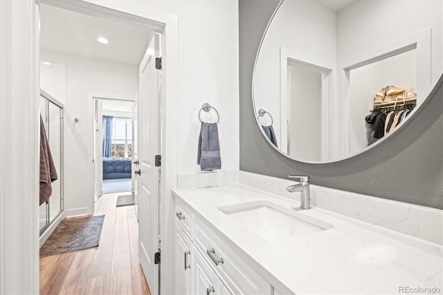 bathroom featuring vanity, wood-type flooring, and a shower with door