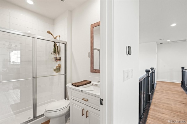 bathroom featuring vanity, wood-type flooring, toilet, and an enclosed shower