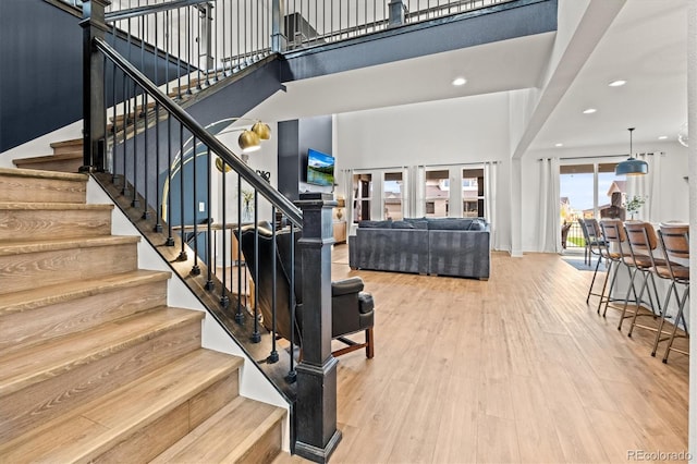 stairs with hardwood / wood-style flooring and a high ceiling