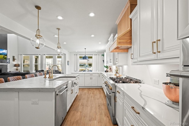 kitchen with appliances with stainless steel finishes, hanging light fixtures, a kitchen island with sink, and white cabinets