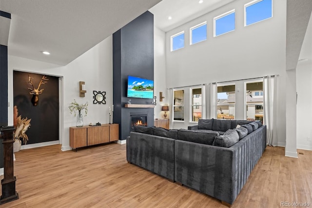 living room with a textured ceiling, a high ceiling, and light wood-type flooring