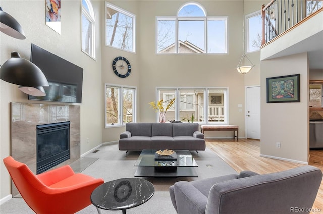 living area with baseboards, a high ceiling, a fireplace, and wood finished floors