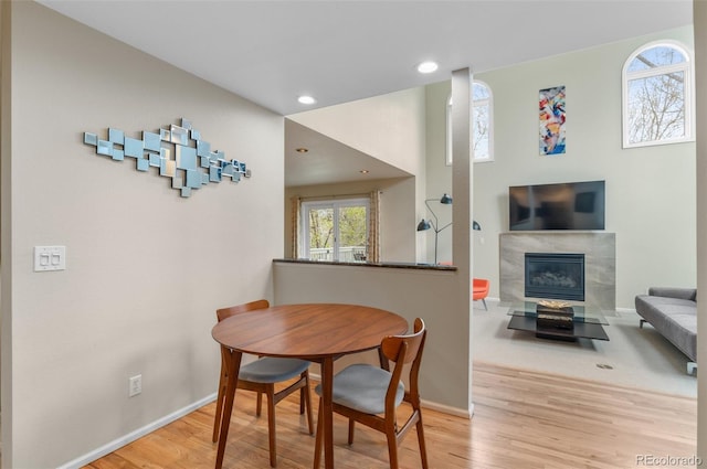 dining space featuring baseboards, a fireplace, recessed lighting, and wood finished floors