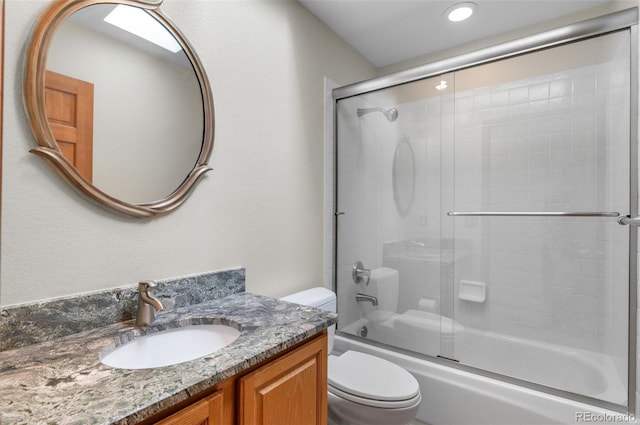 full bathroom featuring vanity, bath / shower combo with glass door, and toilet
