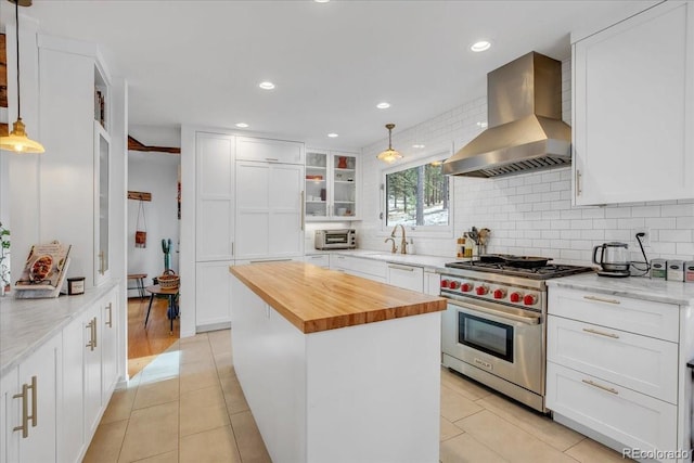 kitchen with pendant lighting, a kitchen island, white cabinetry, luxury stove, and ventilation hood