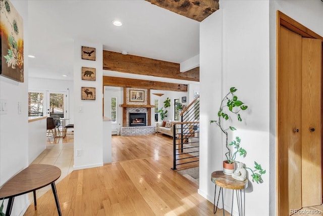 foyer featuring hardwood / wood-style floors, beamed ceiling, and a fireplace