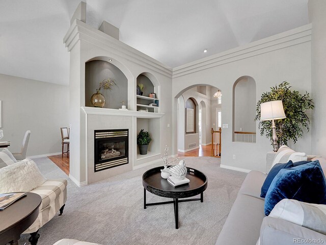 946 Champion Cir, Longmont, CO 80503 - living room with built in shelves, carpet flooring, arched walkways, baseboards, and a glass covered fireplace