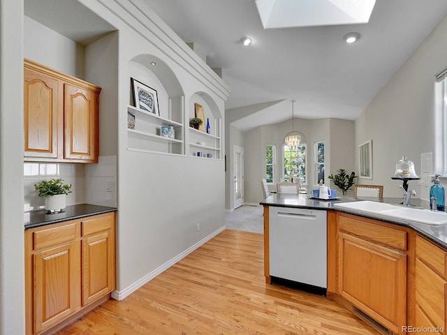 946 Champion Cir, Longmont, CO 80503 - kitchen featuring dishwashing machine, a sink, a skylight, dark countertops, and vaulted ceiling