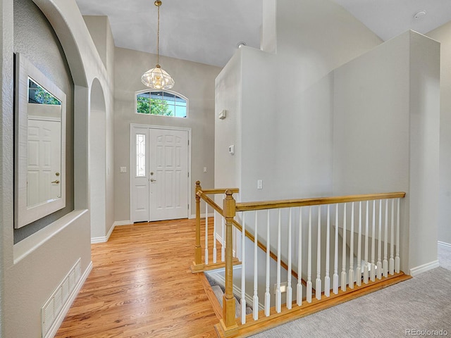 946 Champion Cir, Longmont, CO 80503 - entryway with baseboards, wood finished floors, arched walkways, a chandelier, and high vaulted ceiling