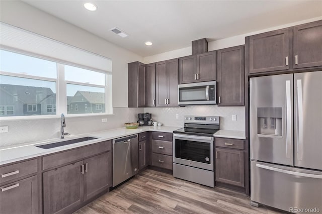 2080 Alcott Way, Broomfield, CO 80023 - kitchen with stainless steel appliances, a sink, dark brown cabinetry, decorative backsplash, and light countertops