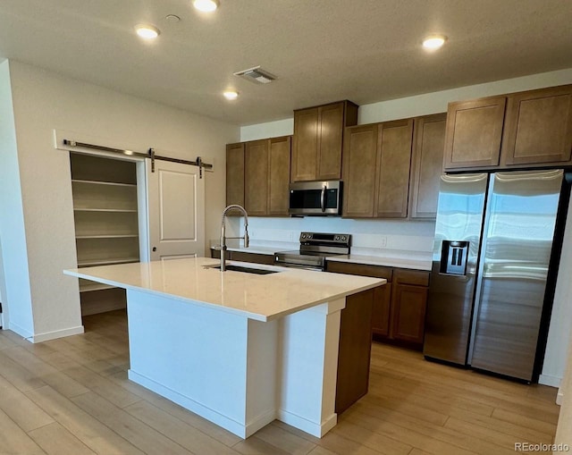 6153 N Ceylon St Unit 206, Denver, CO 80249 - kitchen with appliances with stainless steel finishes, light wood finished floors, light countertops, a kitchen island with sink, and recessed lighting