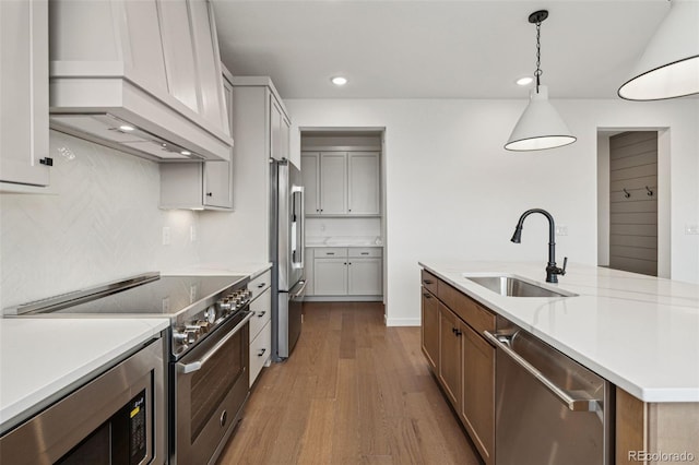 kitchen featuring custom exhaust hood, high quality appliances, dark wood-type flooring, sink, and hanging light fixtures