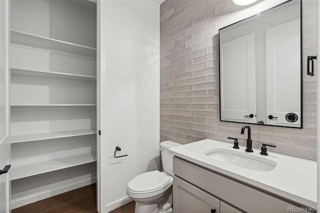 bathroom featuring wood-type flooring, vanity, tasteful backsplash, and toilet