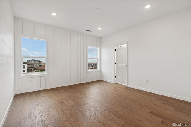 unfurnished room featuring wood-type flooring and wooden walls