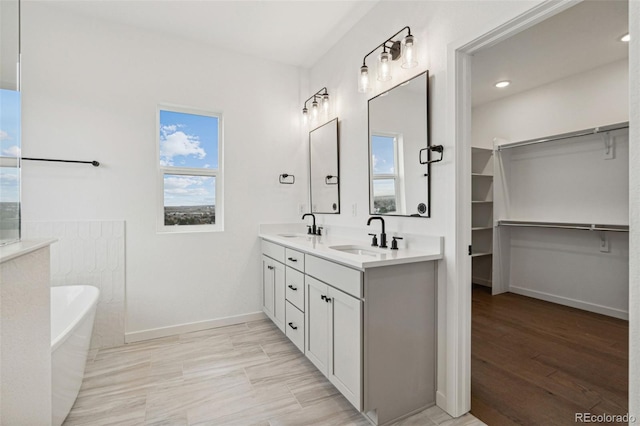 bathroom featuring a bath, wood-type flooring, vanity, and a healthy amount of sunlight