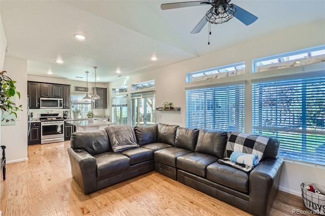 living room featuring ceiling fan, vaulted ceiling, and light hardwood / wood-style flooring