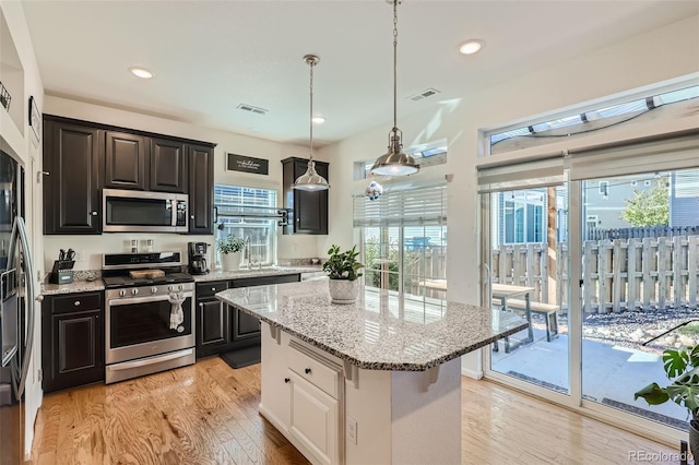 kitchen featuring light wood-type flooring, appliances with stainless steel finishes, a center island, and a wealth of natural light