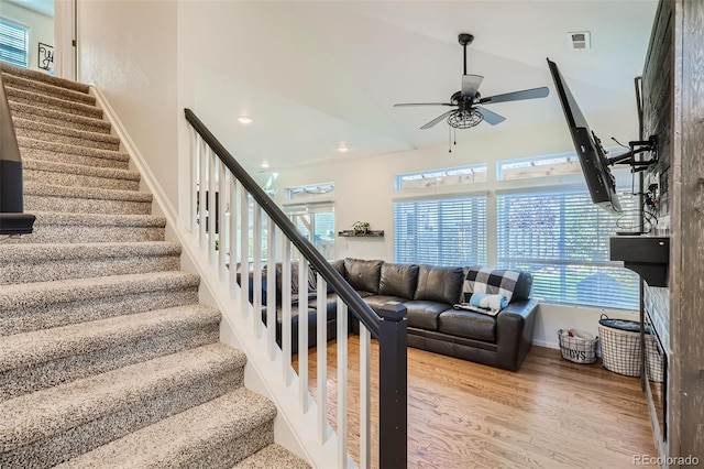 staircase featuring wood-type flooring, lofted ceiling, ceiling fan, and a healthy amount of sunlight