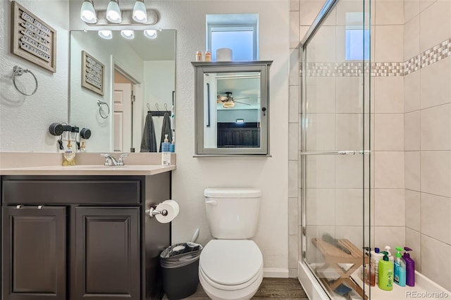 bathroom featuring vanity, wood-type flooring, an enclosed shower, and toilet