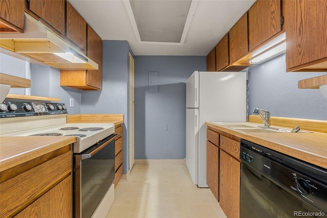 kitchen featuring white appliances, under cabinet range hood, light countertops, and a sink