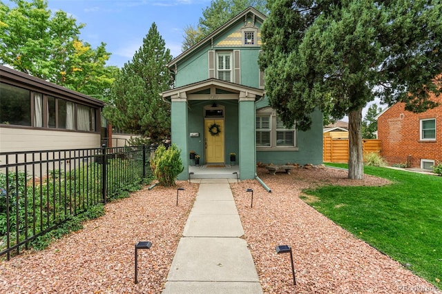 victorian house featuring fence, a front lawn, and stucco siding