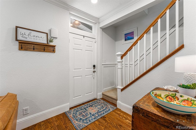 entryway with baseboards, a textured wall, stairway, wood finished floors, and crown molding